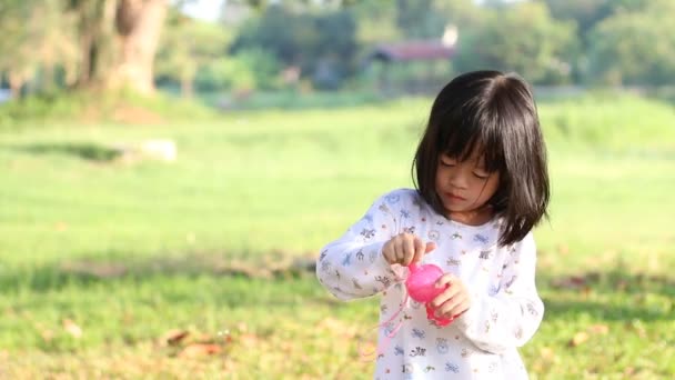 Cute little girl blowing a soap bubbles, Green garden background. — Stock Video