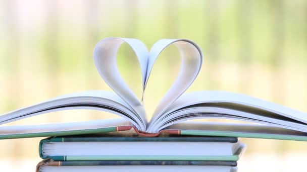 Book stack open page heart shape in wind, green garden background