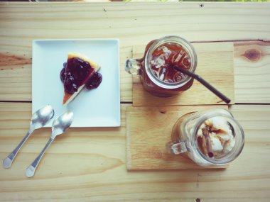 Buz kahve ve blueberies peynir kek üzerine ahşap masa, vintage.