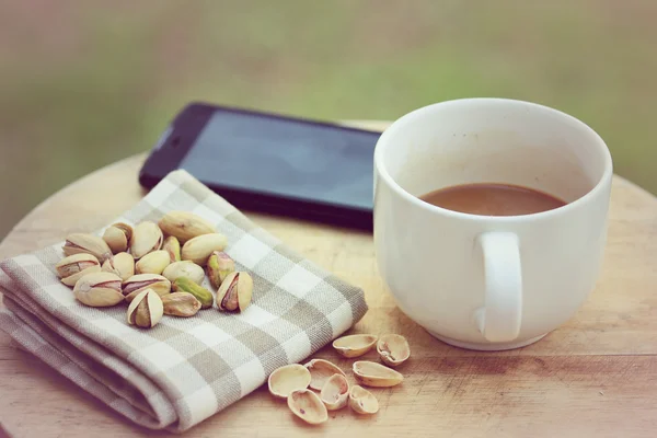 Pistacho y taza de café blanco sobre fondo de madera . —  Fotos de Stock