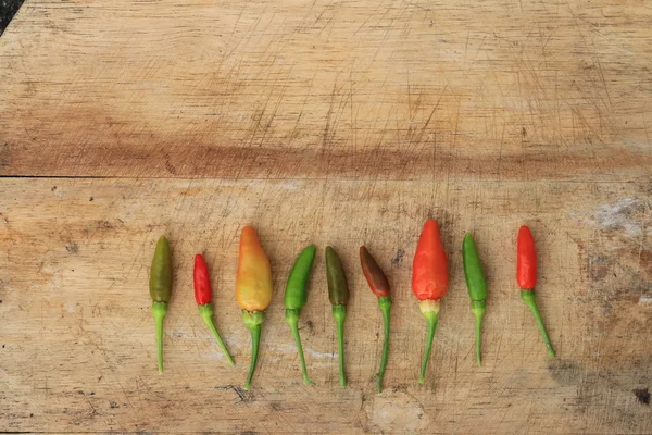 Vermelho verde e marrom Chili em fundo de madeira — Fotografia de Stock