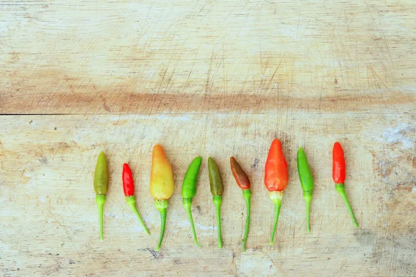 Vermelho verde e marrom Chili em fundo de madeira — Fotografia de Stock