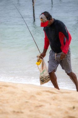 Balıkçılar sahilde kafası balık dolu bir çantayla saatlerce balık tutarak yürüyor..