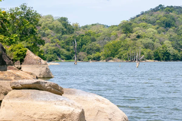 Water level marks in the rocks on the shore of a tank, scenic natural forest environment, slow breeze, and calm waters in Buduruwagala Reservoir,