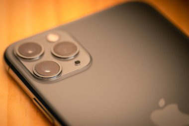 Galle, Sri Lanka - 02 19 2021: Apple iPhone 11 profesyonel akıllı mobil cihaz ahşap masa arkasında yakın plan fotoğraf. Koyu renkli gri Apple logosu ve arkada üç kamera ve sensör..