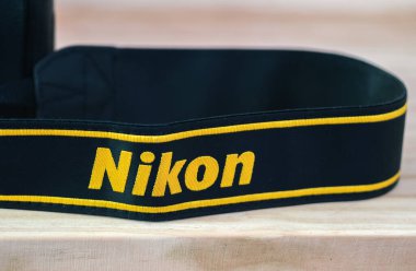 Galle, Sri Lanka - 02 17 2021: Nikon DSLR kamera kayışı ahşap masa üzerinde yakın plan, yepyeni Nikon logosu sarı işlemeli siyah kurdele, profesyonel kalitede fabrika ürünü.