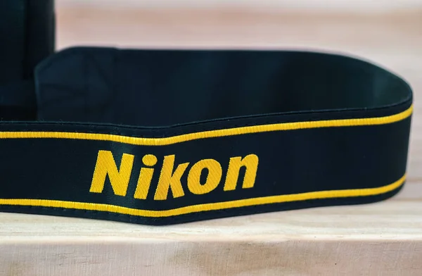 Galle, Sri Lanka - 02 17 2021: Nikon DSLR kamera kayışı ahşap masa üzerinde yakın plan, yepyeni Nikon logosu sarı işlemeli siyah kurdele, profesyonel kalitede fabrika ürünü.