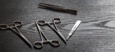 Hemostatik forseps makas ve makas tahta bir masanın üstüne saçılmış..