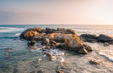 Galle Kalesi sahilinde güzel bir kaya oluşumu, akşam ışığında parlayan, kayaların manzarası ve günbatımı gökyüzü..