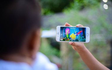 Small baby watching a cartoon on a mobile phone, parents using mobile videos to stop babies cry. The concept of developing childhood learning. Girl Holding the mobile device in front of the kid.