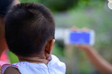 Small baby watching a cartoon on a mobile phone, parents using mobile videos to stop babies cry. The concept of developing childhood learning. Girl Holding the mobile device in front of the kid.