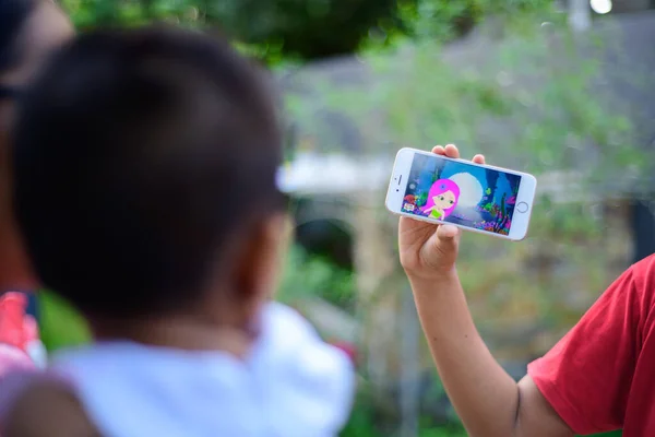 Galle, Sri Lanka - 06 20 2021: Small kids watching a cartoon, The concept of developing childhood learning. Girl Holding the mobile device in front of a kid.