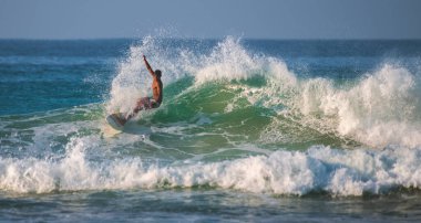 Kabalana, Sri Lanka - 03 26 2023: Genç sörfçü, sabah ışığı, güzel sprey.