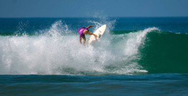 Ahangama, Sri Lanka - 03 26 2023: Pro sörfçü kapalı yeşil dalgada beyaz köpüğü kesmeye çalışıyor.