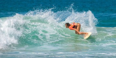 Ahangama, Sri Lanka - 03: 26: 2023 Kesintili manevra yapan çekici sörfçü kız, arkasında güzel bir su spreyi, Red Bull sörf yarışmasında büyük denge ve çeviklik gösterisi.