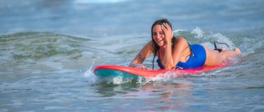 Weligama, Sri Lanka - 10 11 2022: Sörf tahtasında uzanan, tropik plajda süzülen ve akşamları sörf yapmaktan keyif alan güzel büyük beden kız.