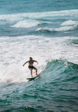 Mirissa, Sri Lanka - 04: 15: 2023: Mirissa Sahili 'nde yeşil bir dalgada dövmeli beyaz erkek sörfçü.