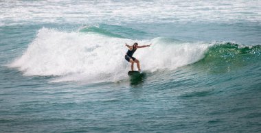 Mirissa, Sri Lanka - 04: 15 2023: Sörfçü güçlü bir yeşil dalgaya el atarak hız ve dengeyi sağlıyor.