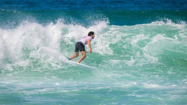 Weligama, Sri Lanka - 05 04 2023: Sörfçü çarpan dalgalara karşı güçlü bir turkuaz dalga, beceri ve denge sürüyor. Tropikal bir sahil cennetinde sörf yapmanın heyecanı ve enerjisi.