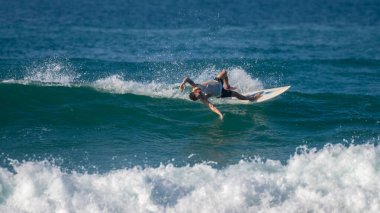 Ahangama, Sri Lanka - 02: 13 2025 Sörf tahtasından düşen bir erkek sörfçü kırılan bir dalgada dengesini kaybederken çarpıcı bir şekilde bükülüyor.