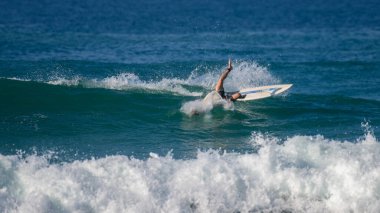 Ahangama, Sri Lanka - 02: 13 2025 Sörf tahtasından düşen bir erkek sörfçü kırılan bir dalgada dengesini kaybederken çarpıcı bir şekilde bükülüyor.