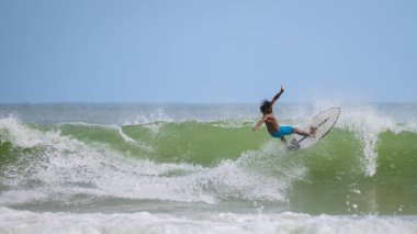 Weligama, Sri Lanka - 05: 20 2023: Patlayıcı enerjiyle dalgayı fırlatmaya hazır sörfçü. Sörfçü, sörf hareketinin dramatik bir anında elit atletizm ve stil sergiliyor
