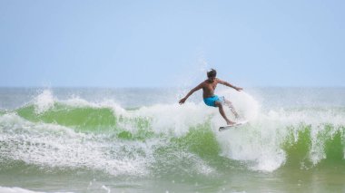 Weligama, Sri Lanka - 05: 20 2023: Patlayıcı enerjiyle dalgayı fırlatmaya hazır sörfçü. Sörfçü, sörf hareketinin dramatik bir anında elit atletizm ve stil sergiliyor