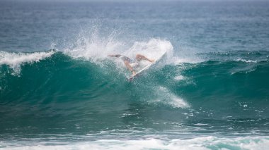 Profesyonel sörfçüler kırılma dalgasında başarısız oldular. Dalganın içine düştüğünde etrafındaki su çarpıcı bir şekilde püskürtülüyor..