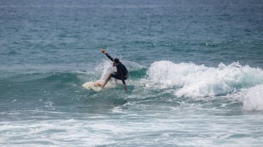 Midigama, Sri Lanka - 03 05: 2024: Erkek sörfçü temiz bir dalgada kesintiye uğruyor, vücudu düşük ve dengeli, tek kolu kontrollü, etrafını sprey kapladıkça oyuyor. Sekans-5-01