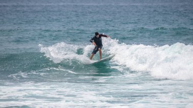 Midigama, Sri Lanka - 03 05: 2024: Erkek sörfçü temiz bir dalgada kesintiye uğruyor, vücudu düşük ve dengeli, tek kolu kontrollü, etrafını sprey kapladıkça oyuyor. Sıra-5-05