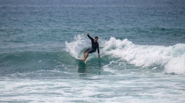 Midigama, Sri Lanka - 03 05: 2024: Erkek sörfçü temiz bir dalgada kesintiye uğruyor, vücudu düşük ve dengeli, tek kolu kontrollü, etrafını sprey kapladıkça oyuyor. Sıra-5-03