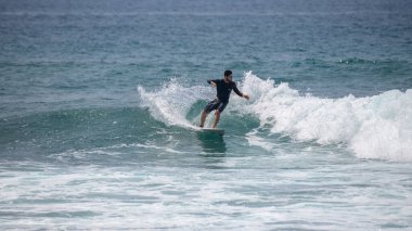 Midigama, Sri Lanka - 03 05: 2024: Erkek sörfçü temiz bir dalgada kesintiye uğruyor, vücudu düşük ve dengeli, tek kolu kontrollü, etrafını sprey kapladıkça oyuyor. Sekans-5-04