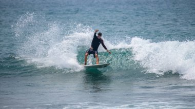 Midigama, Sri Lanka - 03 05: 2024: Erkek sörfçü temiz bir dalgada kesintiye uğruyor, vücudu düşük ve dengeli, tek kolu kontrollü, etrafını sprey kapladıkça oyuyor. Sıra-6-03