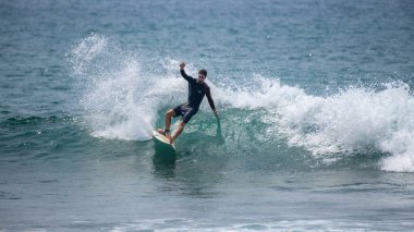 Midigama, Sri Lanka - 03 05: 2024: Erkek sörfçü temiz bir dalgada kesintiye uğruyor, vücudu düşük ve dengeli, tek kolu kontrollü, etrafını sprey kapladıkça oyuyor. Sıra-6-02