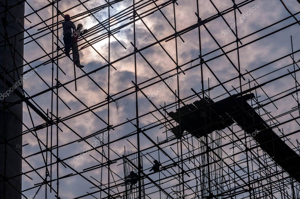 Silueta de los trabajadores alta en andamios en un sitio de