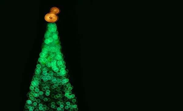 Odaklanmamış yeşil bokeh ışıklarından siyah fonda yılbaşı ağacı. Müzik posteri, ses kaydı, metin alanı için yaratıcı öge. 