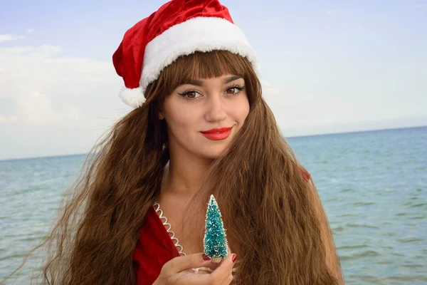 Happy and beautiful girl Santa Claus on the beach. — Stock Photo, Image