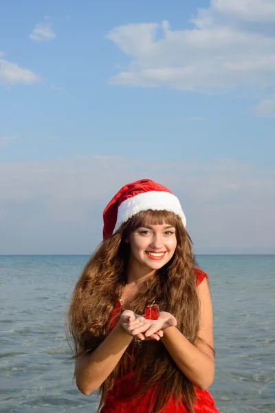 Gelukkig en mooi meisje santa claus op het strand. — Stockfoto