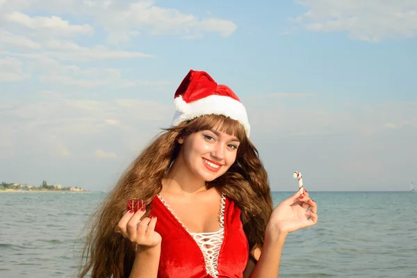 Gelukkig en mooi meisje santa claus op het strand. — Stockfoto