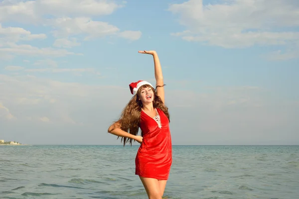 Glücklich und schön mädchen weihnachtsmann am strand. — Stockfoto