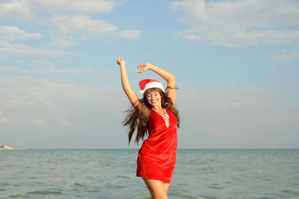 Happy and beautiful girl Santa Claus on the beach. — Stock Photo, Image