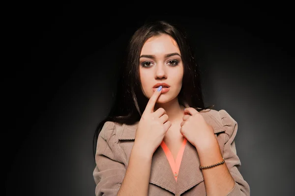 Schöne Brünette mit langen Haaren auf dunklem Hintergrund — Stockfoto