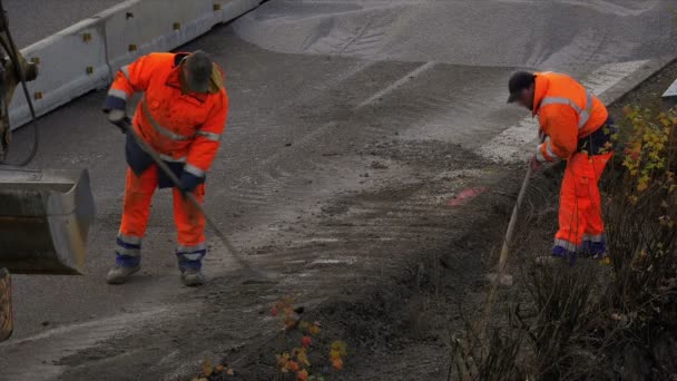 Två byggnadsarbetare skotta grus på motorväg — Stockvideo