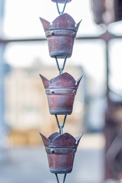 Ornamental cast metal water cup on a traditional Japanese rain chain, or \