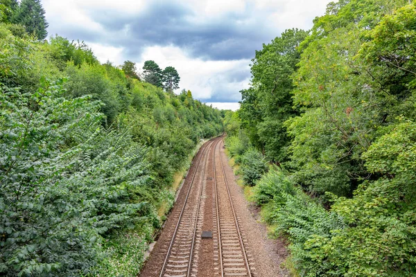 Marple, Cheshire, UK. Summer view of railway track of the Hope Valley Line from Manchester Piccadilly to Sheffield, under threatening sky.