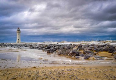 New Brighton 'daki deniz feneri, Merseyside, İngiltere' de, fırtınalı denizde, uzakta rüzgar çiftliği var..