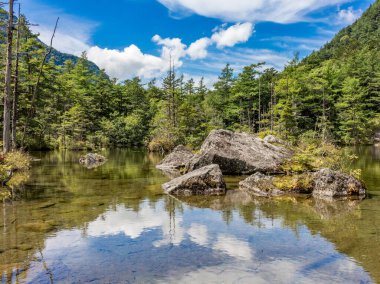 Kaya dolu tenha doğal gölet, mavi bulutlu yaz gökyüzünün yansıması, Japon dağlarında, Kamikochi, Japonya.