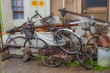 Collection of old discarded bicycles and metal, outside deserted Japanese house, Kanazawa, Ishikawa Prefecture, Japan. clipart