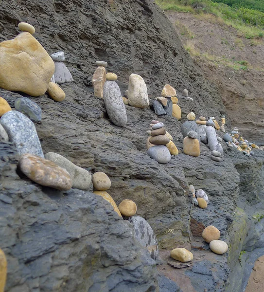 Collection of piled, balanced stones on public beach at Robin Hood\'s Bay, a small fishing village and bay in the North Yorkshire Moors National Park, England.