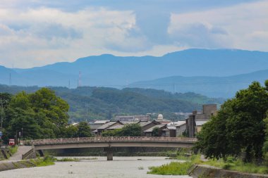 Asanogawa nehri ve köprüsünün uzak dağlarla manzarası. Kanazawa, Ishikawa Bölgesi, Japonya.